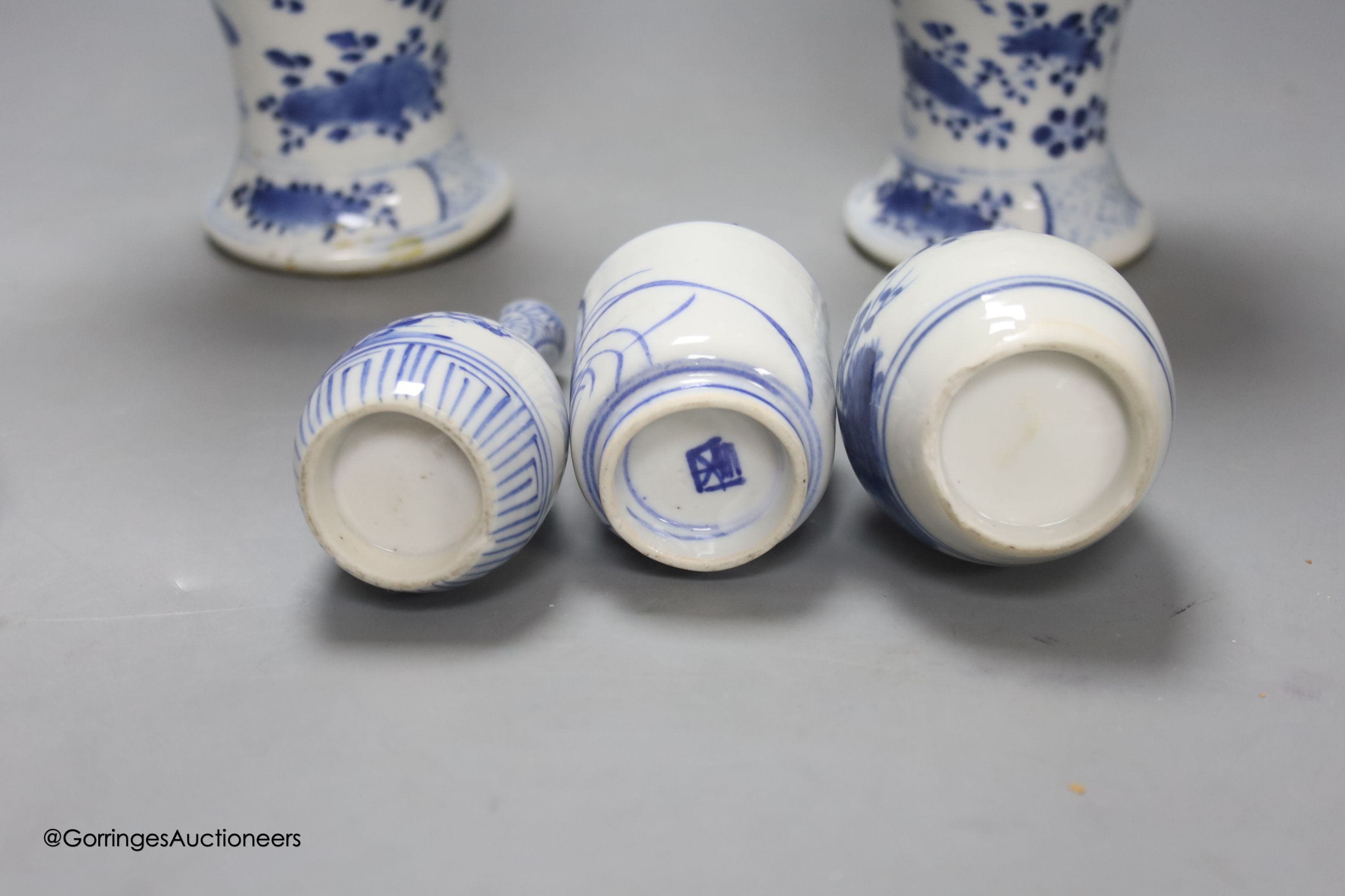 A pair of lidded Chinese blue and white vases, c.1900, Kangxi marks, 23cm high, together with two small Japanese vases, and a cup and saucer (6)